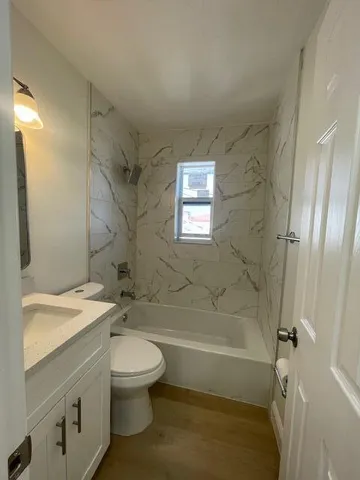 a bathroom with a granite countertop toilet a sink and a bathtub