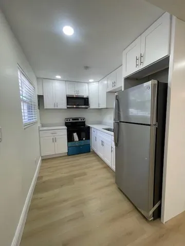 a kitchen with refrigerator a microwave a sink and cabinets