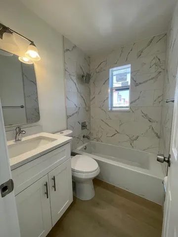 a bathroom with a granite countertop toilet a sink and a bathtub