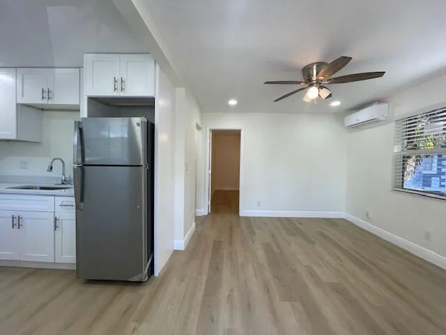 a view of a kitchen with a refrigerator a ceiling fan and wooden floor
