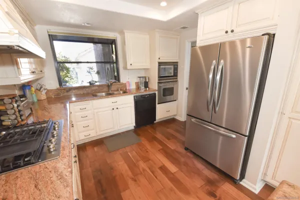 a kitchen with stainless steel appliances a refrigerator sink and wooden floor
