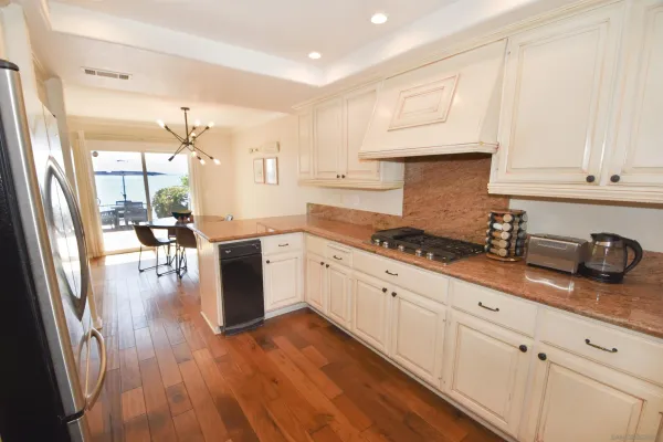 a kitchen with granite countertop stainless steel appliances refrigerator wooden floor and cabinets