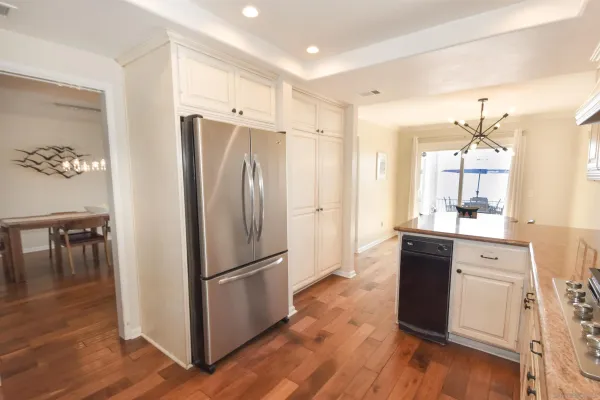 a kitchen with granite countertop a refrigerator a stove a sink and a dining table with wooden floor