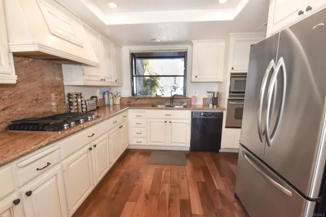 a kitchen with stainless steel appliances a refrigerator sink and wooden floor