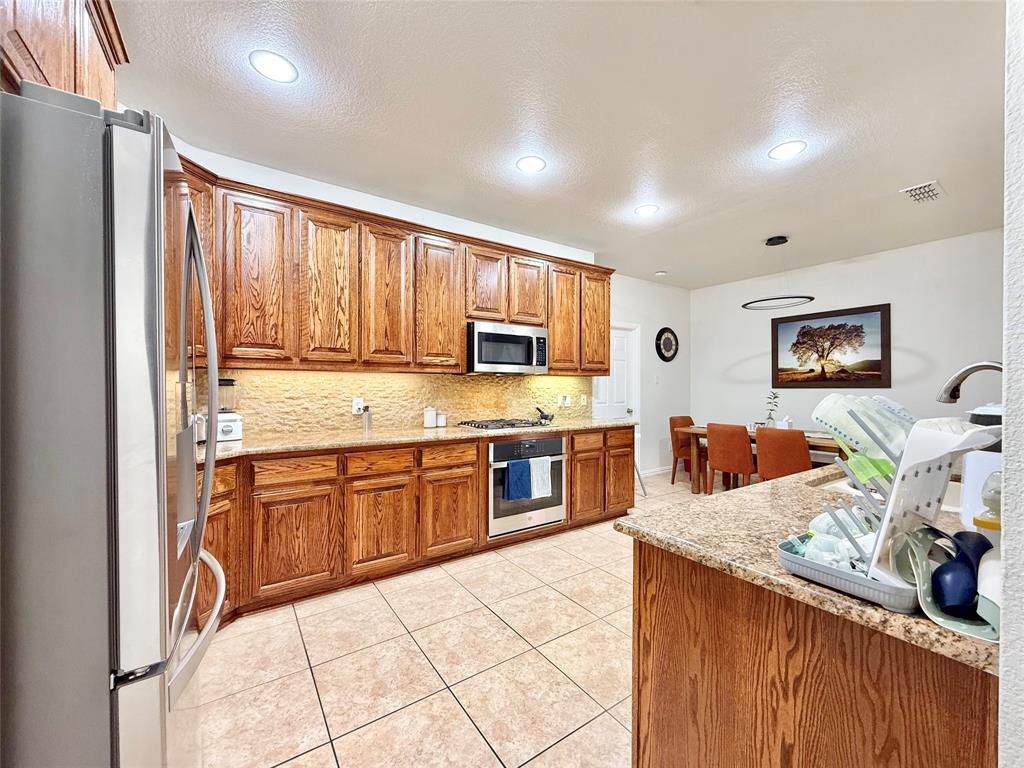 2754 Ridge View Road Frisco, TX 75034 - Photo 10 of 34 a large kitchen with kitchen island granite countertop wooden cabinets a sink and a stove