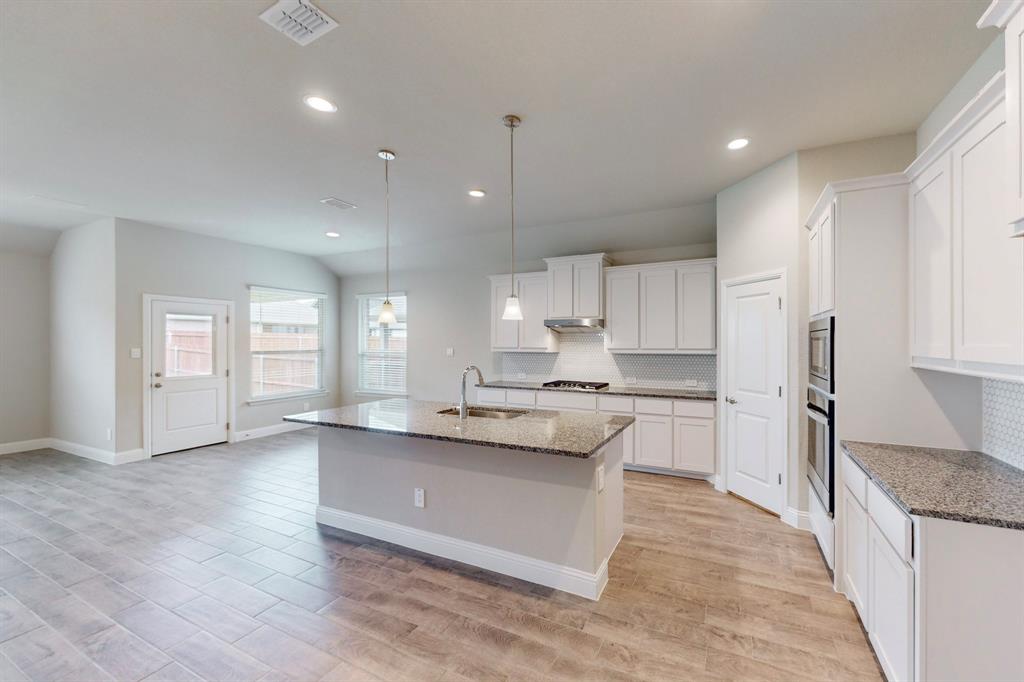 a large kitchen with granite countertop a large counter top a sink stainless steel appliances and cabinets