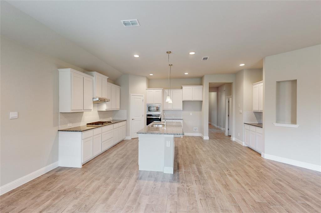 3017 Hampton Path Argyle, TX 76226 - Photo 33 of 37 a kitchen with stainless steel appliances kitchen island wooden floors and white cabinets