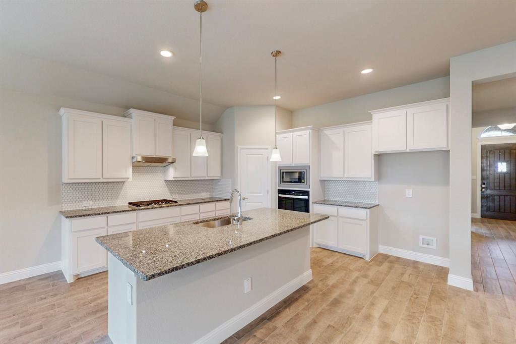 3017 Hampton Path Argyle, TX 76226 - Photo 7 of 37 a large kitchen with kitchen island a stove a sink a refrigerator and white cabinets