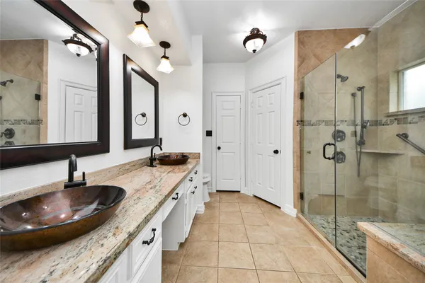 a bathroom with a granite countertop sink a toilet a mirror and shower