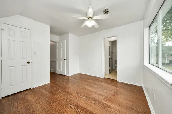 a view of an empty room with a window and wooden floor
