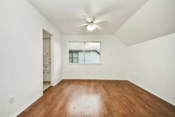 an empty room with wooden floor chandelier fan and windows