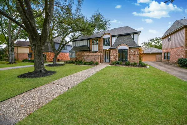 a front view of a house with a yard and trees