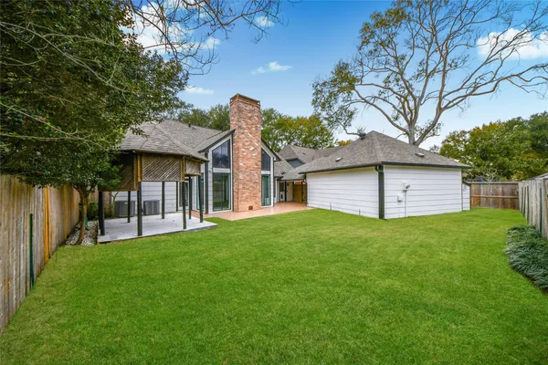 a view of a yard in front of a house with plants and large tree