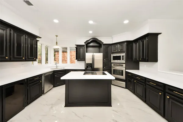 a kitchen with kitchen island granite countertop a sink counter top space appliances and cabinets