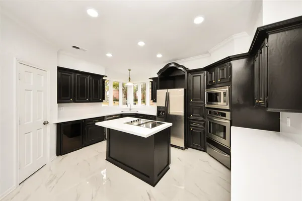 a kitchen with stainless steel appliances kitchen island a stove a refrigerator and a oven