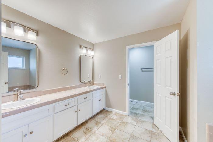 6153 Big Oak Road Sanger, CA 93657 - Photo 12 of 23 a spacious bathroom with a double vanity sink and a mirror
