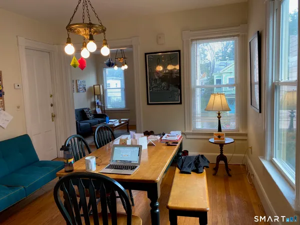 a dining room with wooden floor a chandelier a wooden table and chairs