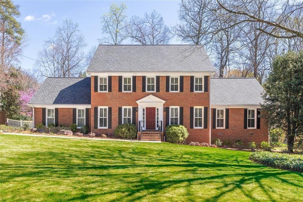 a front view of a house with a garden and trees
