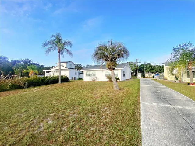a front view of a house with a yard and palm trees
