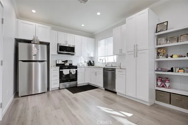 a kitchen with a refrigerator a stove top oven and white cabinets