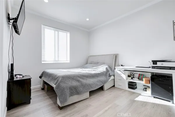 a bedroom with a bed and a flat tv screen on the dresser