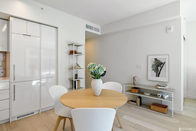 a living room with dining table and a refrigerator