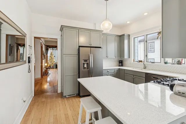 a kitchen with stainless steel appliances a sink dishwasher a refrigerator and a dining table with wooden floor