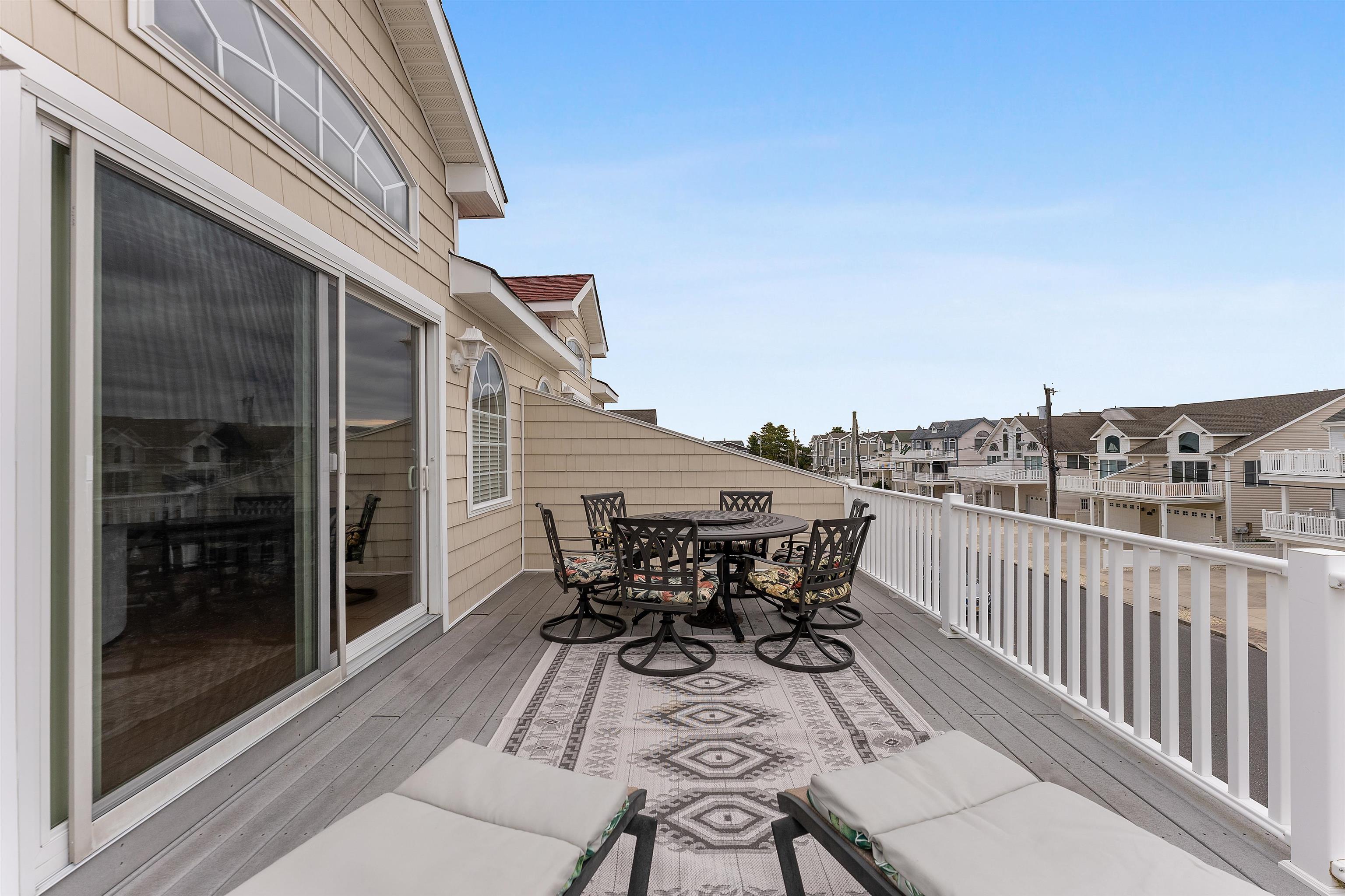 33 74th Street, Unit WEST Sea Isle City, NJ 08243 - Photo 8 of 48 a view of a roof deck with table and chairs and wooden floor