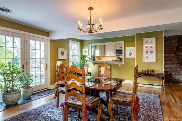 a dining room with wooden floor a chandelier a wooden table and chairs