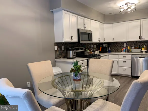 a kitchen with stainless steel appliances kitchen island granite countertop a table and a view of living room