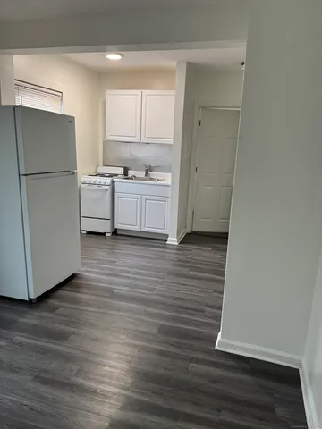 a kitchen with a refrigerator a stove top oven and a wooden floor