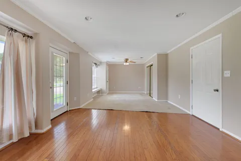 a view of empty room with wooden floor and fan
