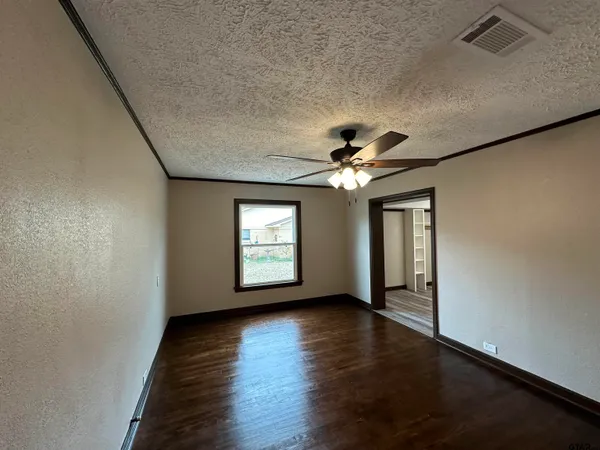 a view of an empty room with a window and wooden floor