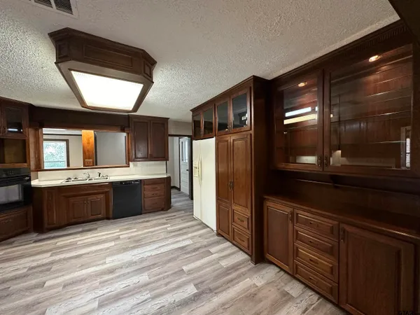 a large kitchen with stainless steel appliances kitchen island granite countertop a refrigerator and a wooden cabinets
