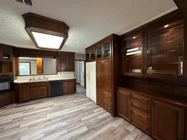 a large kitchen with stainless steel appliances kitchen island granite countertop a refrigerator and a wooden cabinets