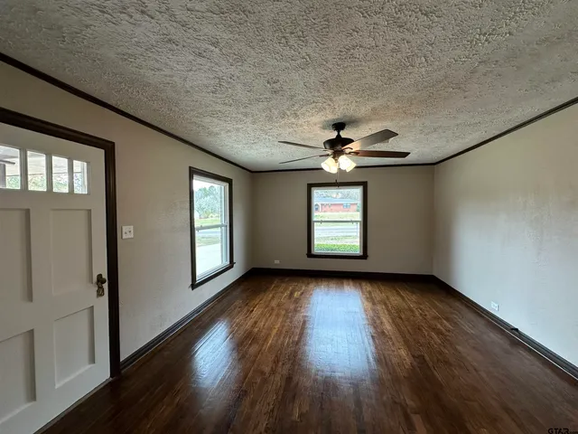 an empty room with wooden floor chandelier and windows