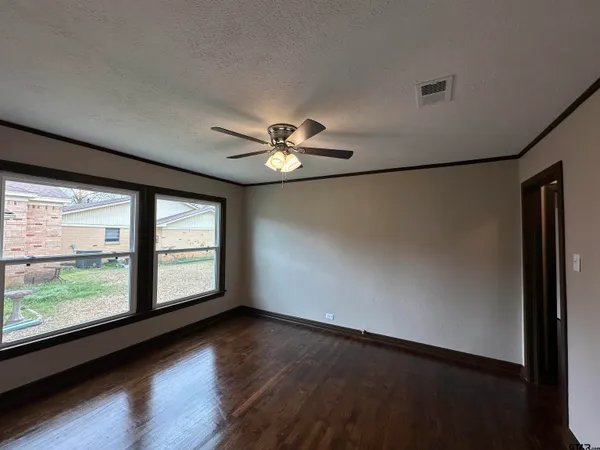 an empty room with wooden floor and windows