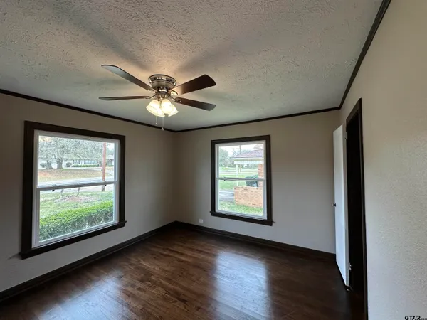 an empty room with wooden floor and windows