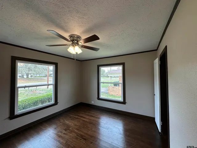 an empty room with wooden floor and windows