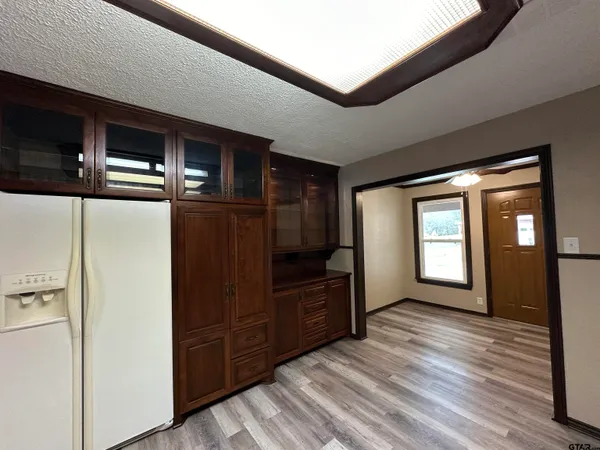 an empty room with wooden floor chandelier fan and windows