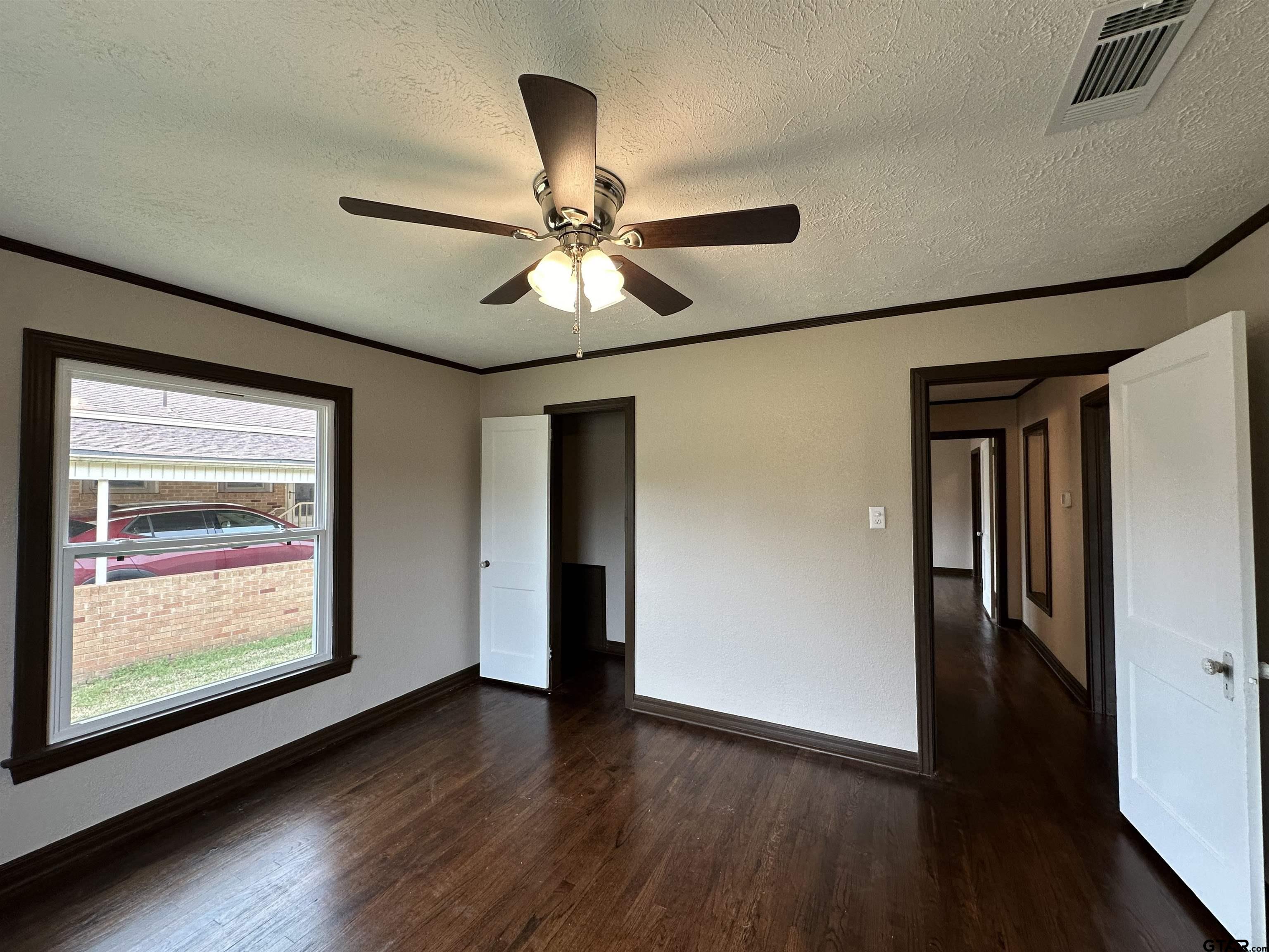 1118 East Main Street Atlanta, TX 75551 - Photo 31 of 34 an empty room with wooden floor chandelier fan and windows