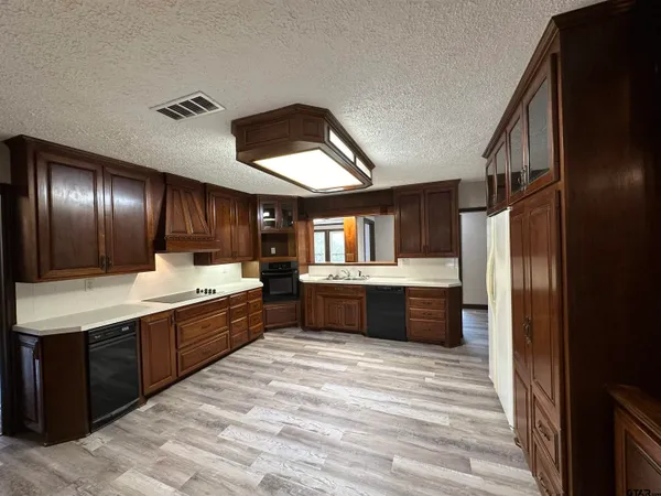 a large kitchen with stainless steel appliances kitchen island granite countertop a refrigerator and a sink
