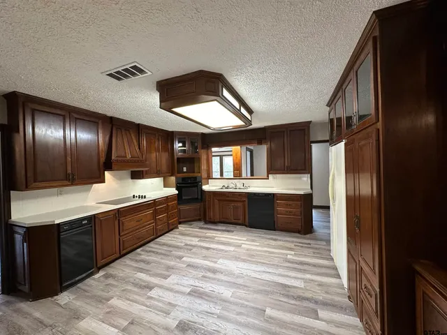 a large kitchen with stainless steel appliances kitchen island granite countertop a refrigerator and a sink