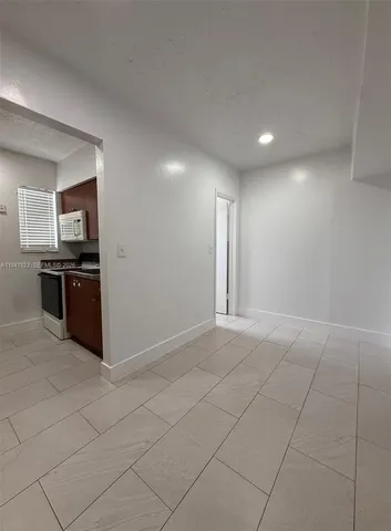 an empty room with kitchen view and window