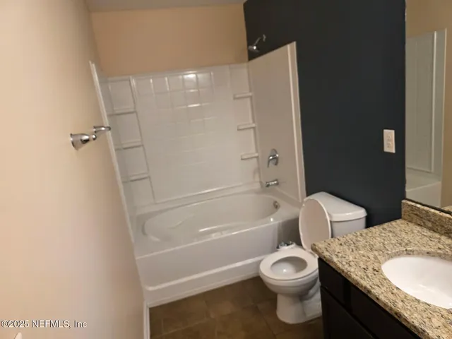 a bathroom with a granite countertop toilet a sink and bathtub