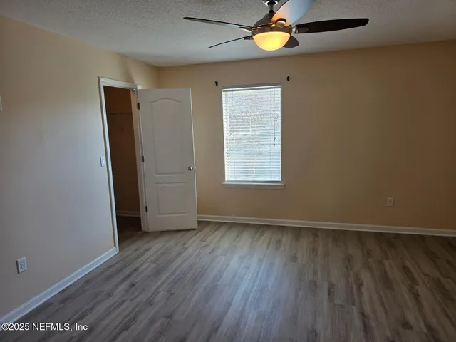 an empty room with wooden floor chandelier fan and windows