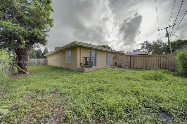a backyard of a house with large trees and wooden fence