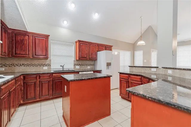 a kitchen with stainless steel appliances granite countertop a sink a stove counter space and a refrigerator