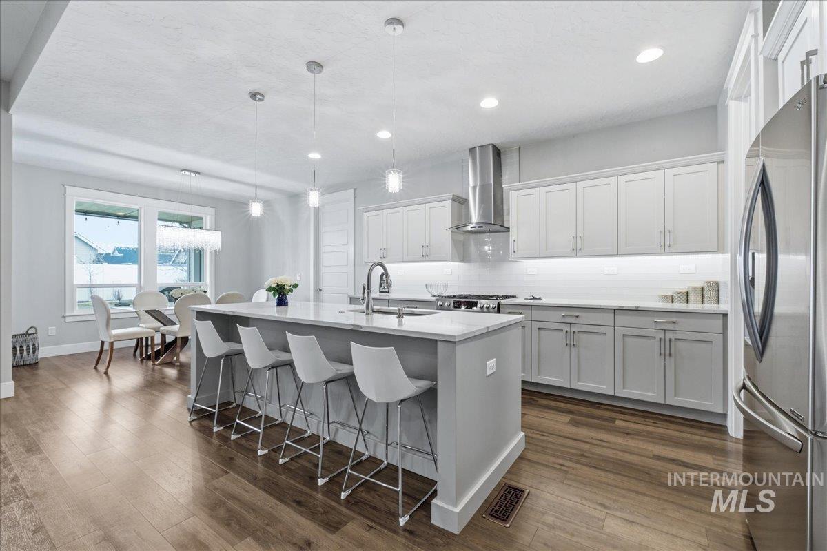 5154 South Twilight Mist Way Meridian, ID 83642 - Photo 13 of 47 Kitchen with a breakfast bar area, an island with sink, stainless steel appliances, light stone counters, and backsplash