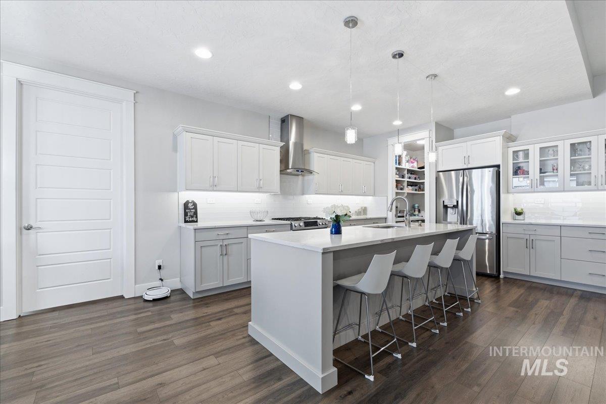 5154 South Twilight Mist Way Meridian, ID 83642 - Photo 14 of 47 Kitchen with a breakfast bar, stainless steel appliances, glass fronted cabinets, a center island with sink, and decorative backsplash